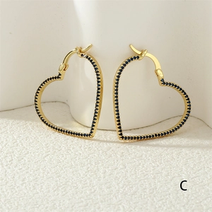 Detail of gold hollow heart hoop earrings with pavé blue cubic zirconia stones