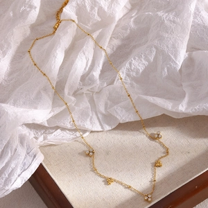 Detail of 18K gold plated bead chain necklace with three zircon stones and small round beads
