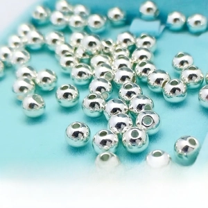 Macro shot of silver plated round beads for jewelry making on blue velvet background