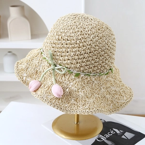 Close-up of handmade straw hat featuring hollow-weave brim and pink fabric tulip charms