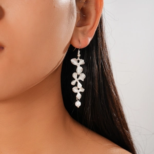 Detailed view of silver flower petal earrings with pearl drops worn on a female model