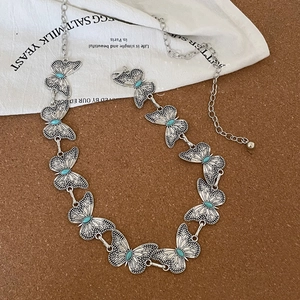Detail of vintage silver butterfly waist chain with turquoise inlay on wood surface