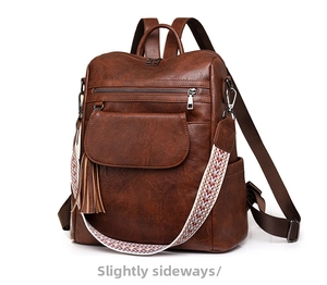 Detail of vintage brown PU leather backpack with tassel and embroidered shoulder strap