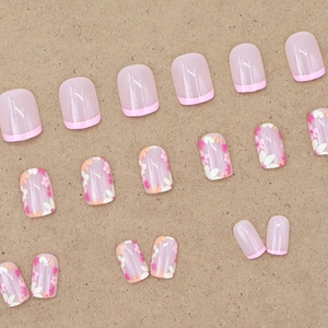 Short square press-on nails with floral patterns and pink french tips on brown background