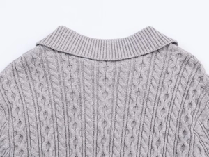 Primer plano detallado de jersey de punto gris con trenzado y cuello de punto acanalado