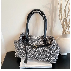 Detail shot of tweed tote bag texture with black leather straps and gold buckle