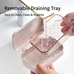 Double-layer pink soap dish with transparent drainage tray being rinsed under water