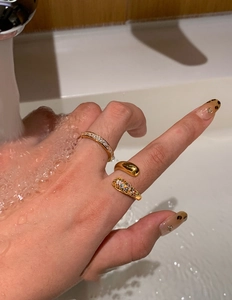 Detailed view of three gold-plated teardrop rings with zircon insets under flowing water