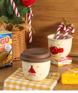 Detail of Christmas Santa ceramic mug with silicone lid beside a holiday themed decor
