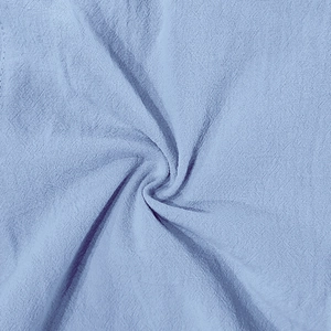 Vue macro du tissu en lin bleu clair respirant montrant la texture du tissage et le drapé