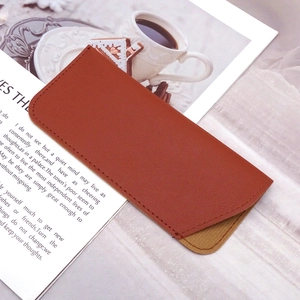 Detailed view of monogram PU leather sunglasses pouch with fine stitching on a magazine