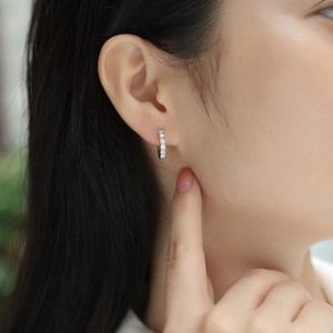 Close-up of minimalist silver hoop earrings with double row moissanite on model ear