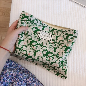 Detail of green floral cotton makeup bag with zip closure and white fabric label