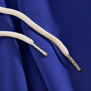 Macro detail of blue knit trousers showing woven drawstring and textured fabric