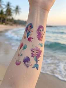 Close-up of waterproof mermaid cartoon tattoos on a child's arm with beach background