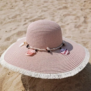 Pink straw sun hat with large brim featuring sea shell beads and white fringe trim