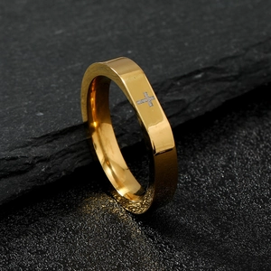 Detail of minimalist gold faceted cross ring on dark textured stone background