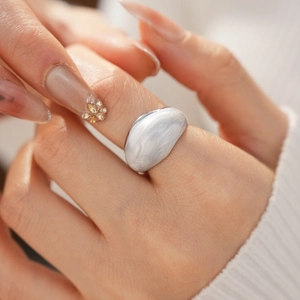 Close-up of a silver minimalist ring with a white marble texture dome worn on a hand