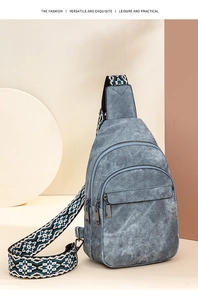 Detail view of a blue denim chest bag featuring a patterned wide woven shoulder strap