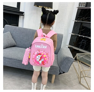 Pink kids backpack with cartoon unicorn pattern and matching pencil case on a young girl
