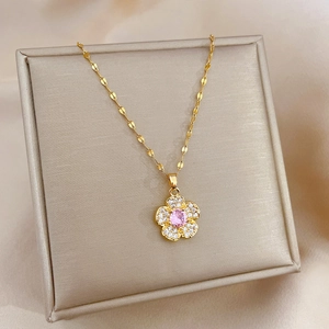 Detail of flower necklace with pink gem and tiny crystals on a beige jewelry box