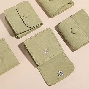 Microfiber jewelry pouches in light green with snap buttons on a beige background
