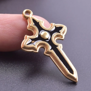 Macro view of gold cross pendant with black filling being held between fingers