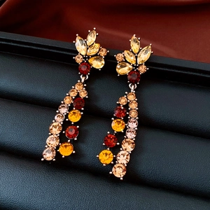 Macro detail of gold-tone vintage flower earrings with amber crystals on black leather