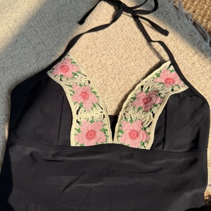 Detail of black halter bikini top with handmade floral crochet trim on V-neckline