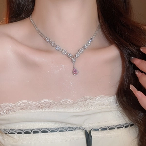 Close-up of a pink pear-cut zircon pendant necklace worn on a woman's collarbone