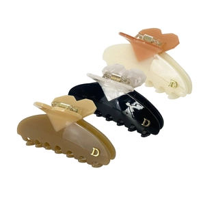 Three elegant heart-shaped hair claws in brown, black, and beige with gold D accents