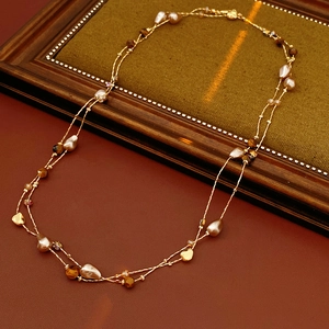 Dettaglio della collana dorata a due strati con perle barocche e pietre occhio di tigre