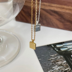 Detail of 925 sterling silver square pendants in gold and silver finish on cross chains