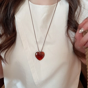 Dettaglio di un ciondolo a cuore rosso scuro su una collana di corda in stile vintage