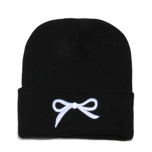 Détail de la maille noire de haute qualité et du nœud blanc brodé sur le bonnet