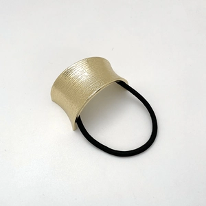 Detail of gold metal U-shaped hair tie with brushed texture and black elastic cord