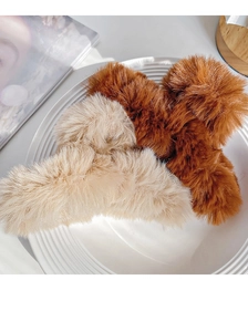 Macro detail of soft beige and brown plush faux fur hair claw clips on ceramic plate