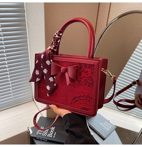 Close-up of red bridal handbag with floral embroidery and bow knot detail