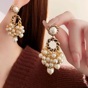 Detail of vintage gold woven hoop earrings with white pearl tassels on a female model