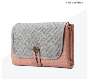 Detail of pink and gray foldable diaper pad showing 3-layer storage and wooden button