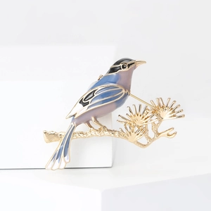 Detail of enamel magpie bird brooch with gold pine branch and purple blue gradient finish