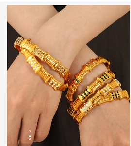 Detail of bamboo style gold bangles with colorful rhinestones on a female wrist