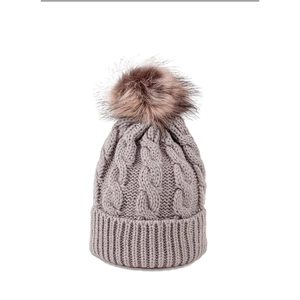 Detailed view of grey cable knit winter hat with fluffy brown faux fur pom pom