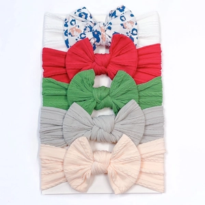 Close-up of 5-pack soft nylon baby headbands with colorful bow designs on white card