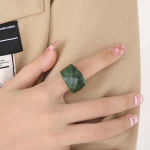 Detailed view of dark green gemstone ring with geometric diamond-cut on gold band