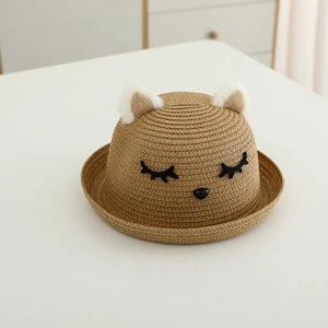 Dettaglio del cappello di paglia per bambini con orecchie di gatto e ricamo del viso carino