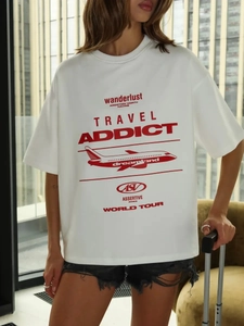 Dettaglio della stampa grafica rossa Travel Addict su t-shirt oversize in cotone stile street