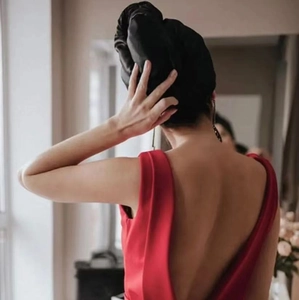 Macro detail of a large black satin hair wrap on long hair paired with a red dress
