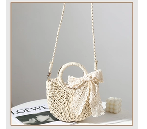 Close-up of beige woven straw handbag featuring a delicate lace bow and round handles