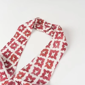 Détail d'un bandeau souple à motifs floraux rouges avec un nœud sur un fond blanc pur
